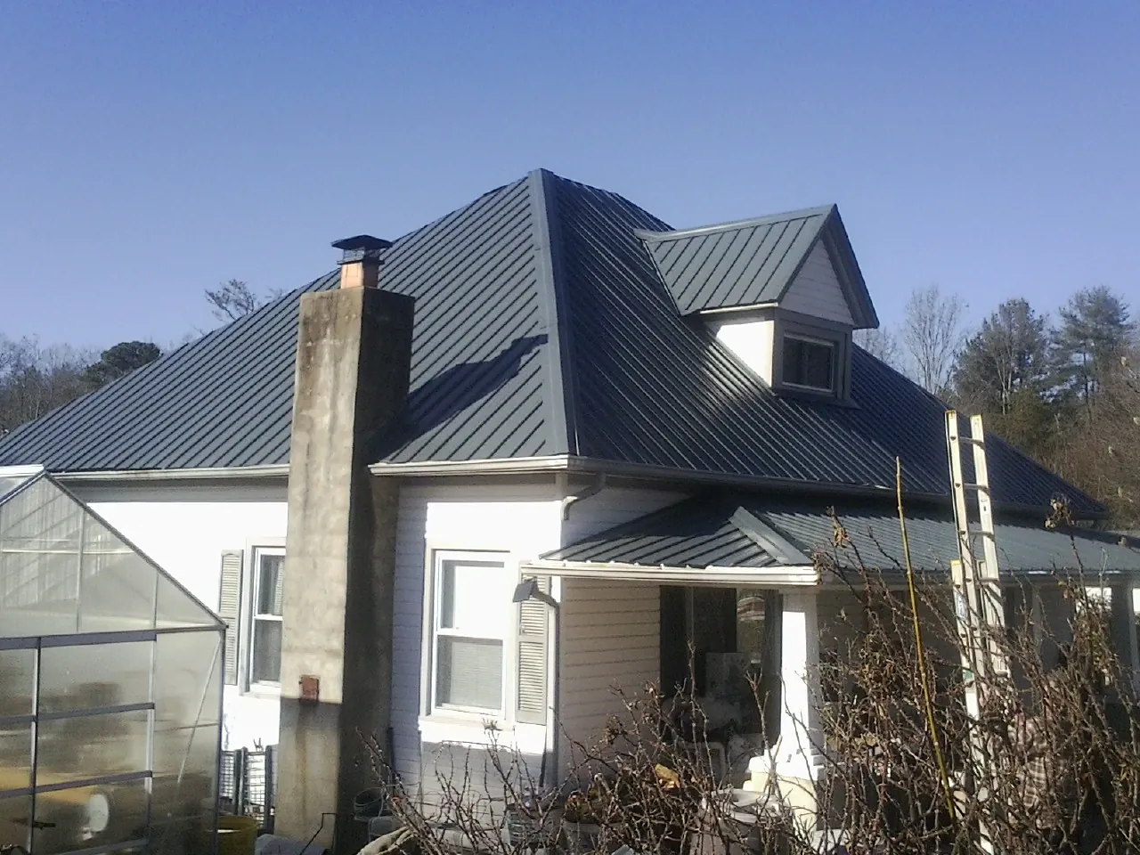 Dark blue standing seam metal roof on a white farmhouse with dormer — Slate & Tile Roof Repair by Roofing Brothers in Pataskala