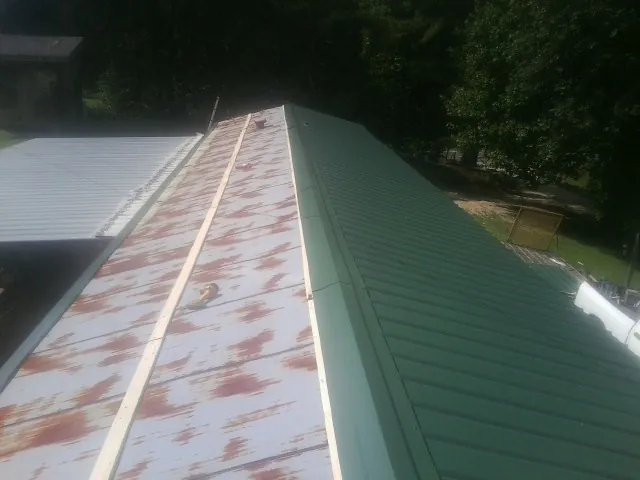 Old rusted panels beside newly installed green metal roofing — Wind Damage Roof Repair by Roofing Brothers in Pataskala