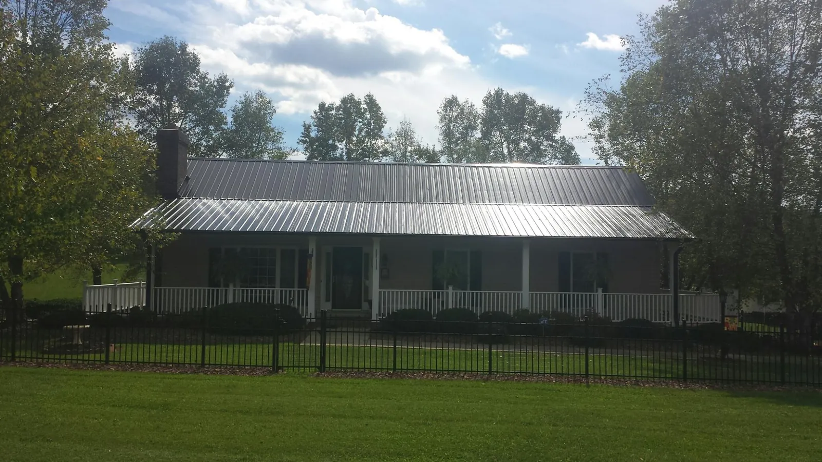 Gray metal roof on a brick ranch with a full width front porch — Gutter Guard Installation work by our crew in Pataskala