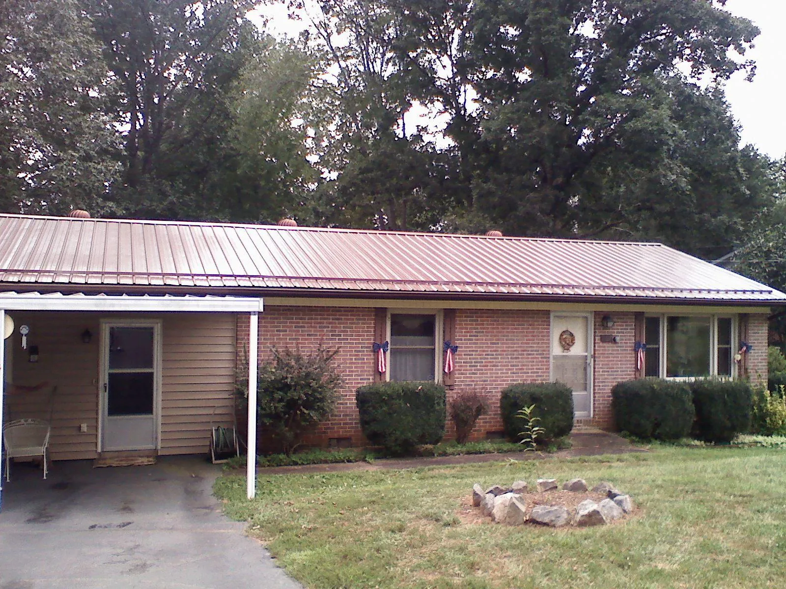 Bronze metal roof and carport on a brick ranch home — Roof Repair work by our crew in Pataskala
