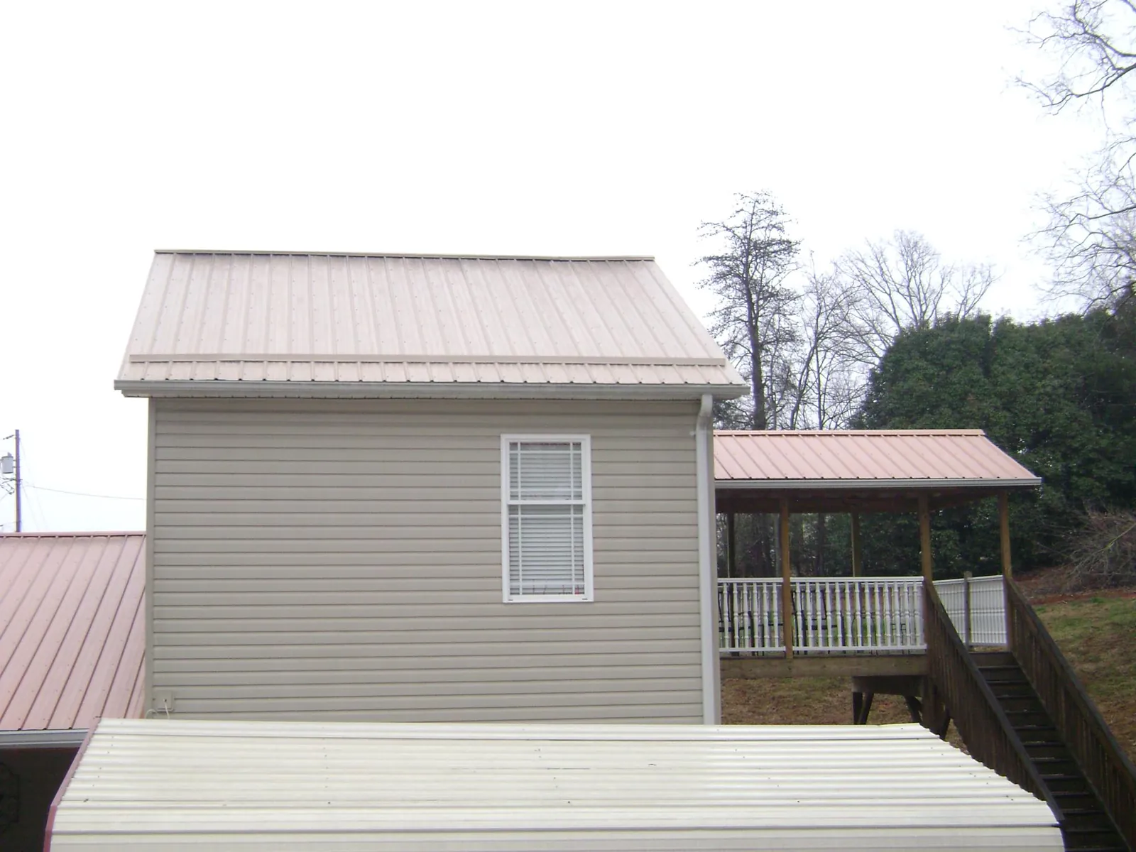 Tan metal roofs on a two story addition and attached porch, from a Roof Replacement job in Pataskala