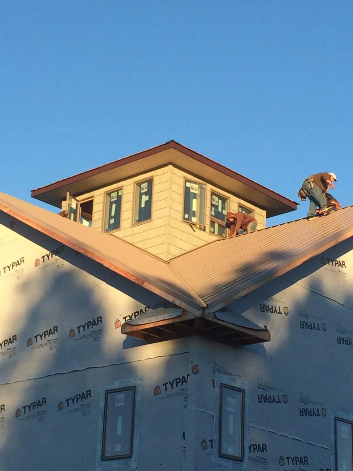 Roofers working around a rooftop cupola on a new metal roof at sunset — Roof Waterproofing in Pataskala by Roofing Brothers